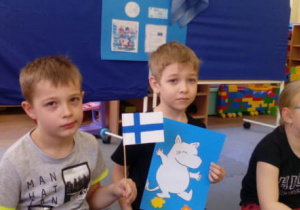 Dwaj chłopcy trzymają flagę Finlandii i obrazek bajki z Finlandii.